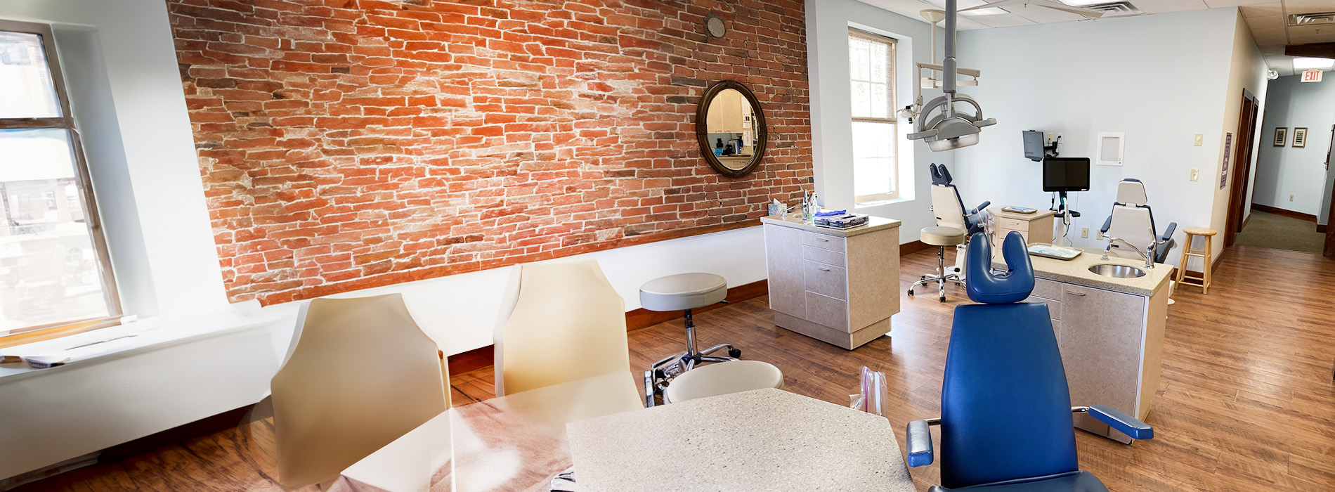 The image shows a person standing against a blue background with a smiling expression, wearing glasses and a light-colored top, appearing to be in front of a digital overlay that obscures part of their body.