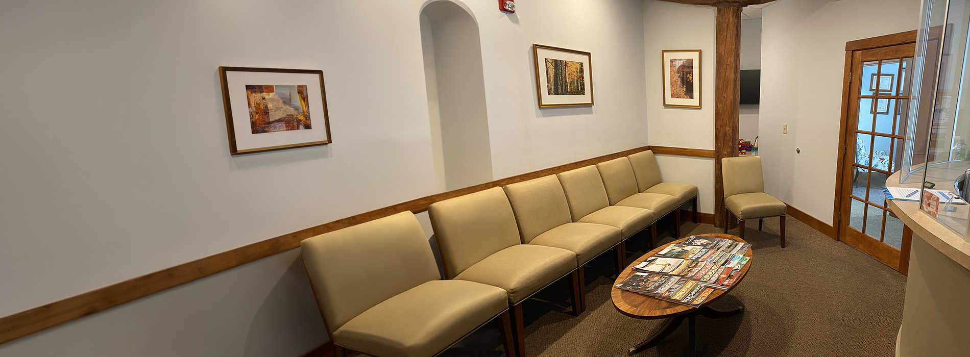 The image features a smiling woman with red hair, wearing a black top, posing for a portrait with her hands on her cheeks, set against a blurred beach background.